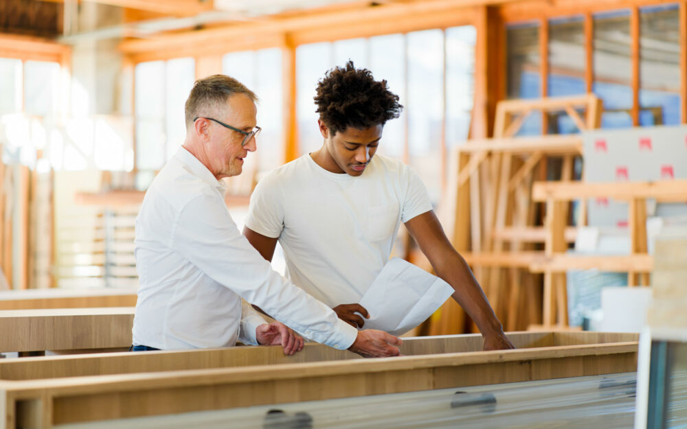 Moment de transmission des savoirs entre un industriel et un de ses jeunes ouvriers. Reportage photo industriel.
