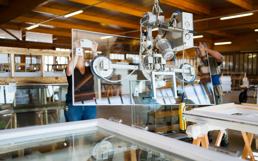 Ouvriers installant le vitrage sur des fenêtres en bois dans l'usine Roux Frères.