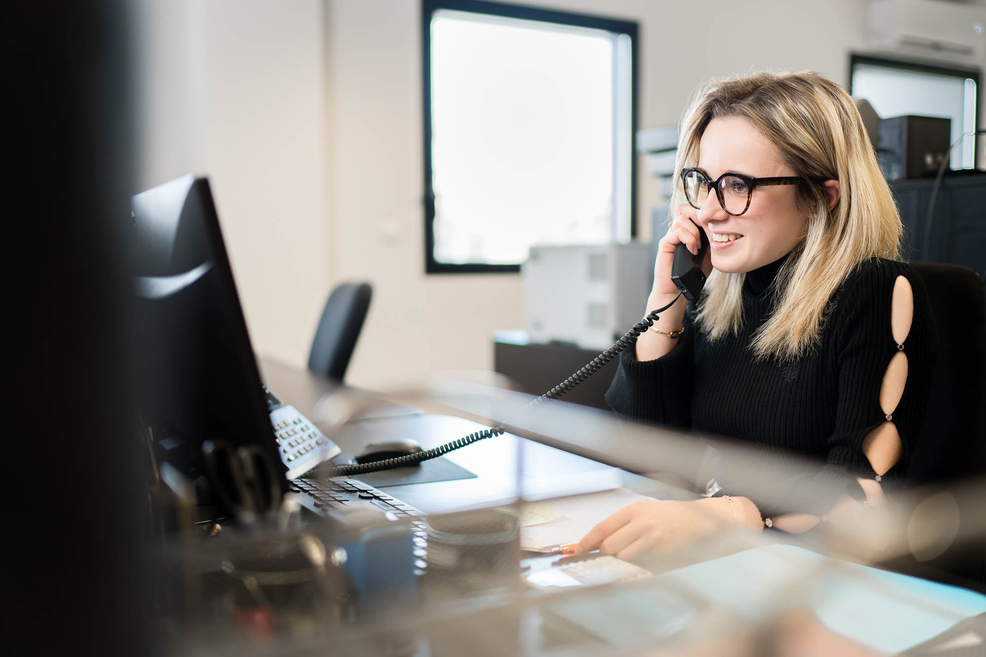 Reportage photo en entreprise : scène de travail au bureau, collaboratrice au téléphone dans les locaux de SOLUTION INDUSTRIE (Vénissieux).